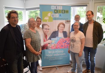 Zes personen staan bij elkaar en kijken de camera in